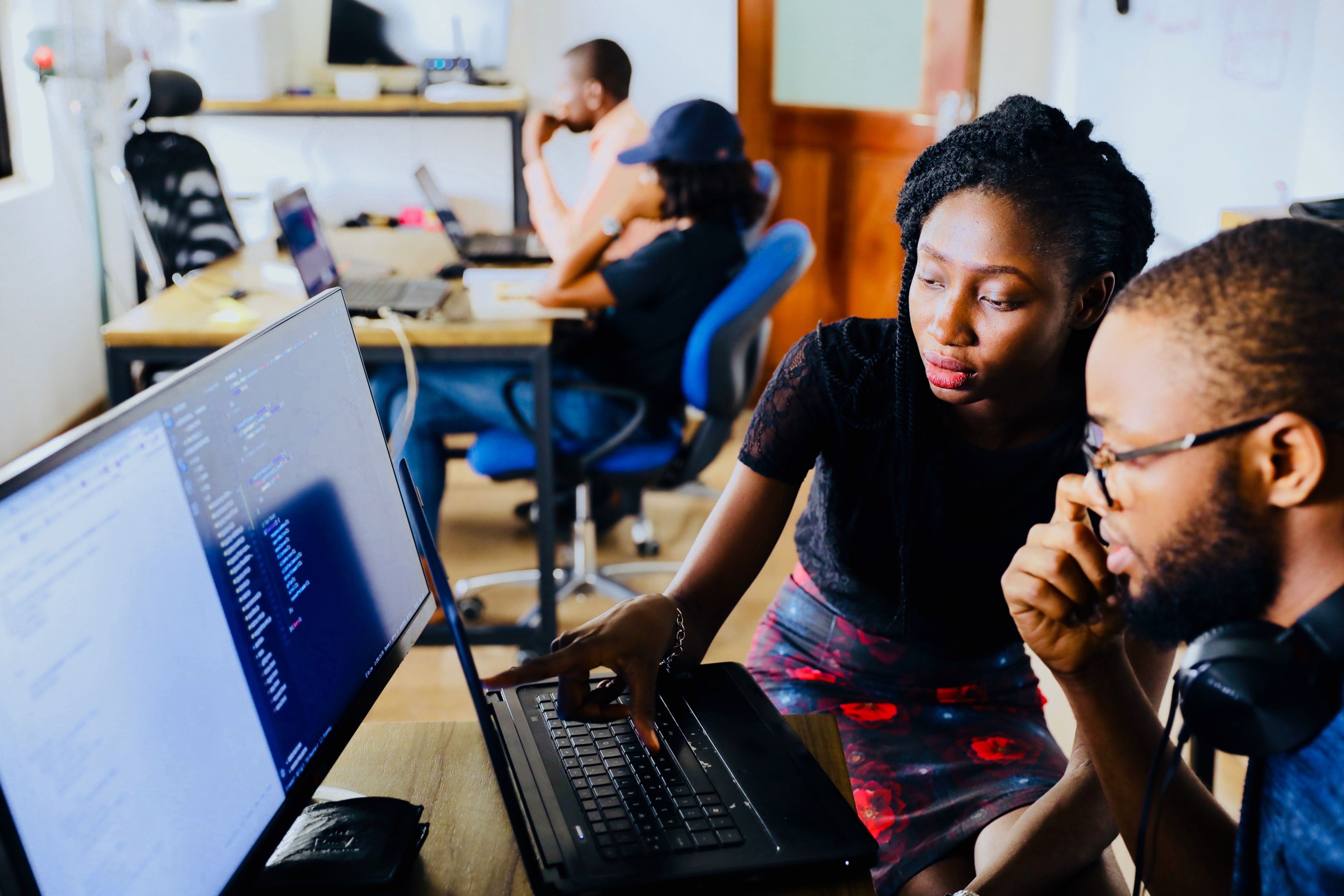 African woman and man coding in front of computer